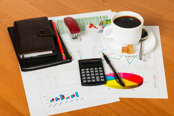 Calculadora, taza de café, cuadernos y otros artículos de papelería en el fondo del escritorio
. - Foto, Imagen