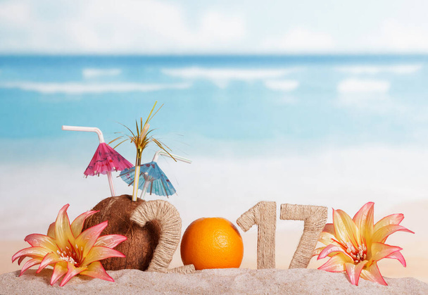 Orange instead of the number 0 in the amount of 2017, coconut and flowers in the sand against the sea. - Φωτογραφία, εικόνα