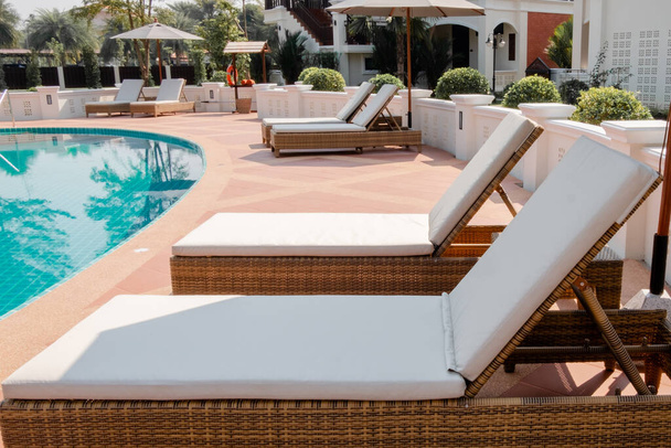 Stühle rund um den Pool mit schönen Sonnenschirmen im Resort des Hotels. - Foto, Bild