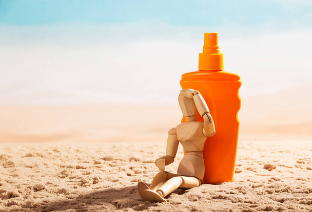 Wooden mannequin and sunscreen at the beach. - 写真・画像
