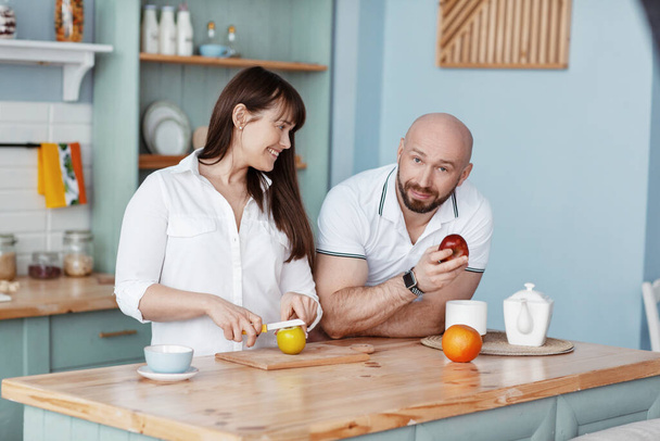 A young beautiful couple prepares Breakfast together in the kitchen on a weekend morning. Romantic relationships, love, family - Fotoğraf, Görsel
