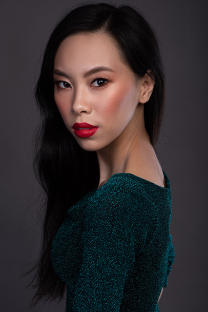 Retrato de mujer asiática con labios rojos en vestido en el estudio sobre fondo oscuro
 - Foto, imagen