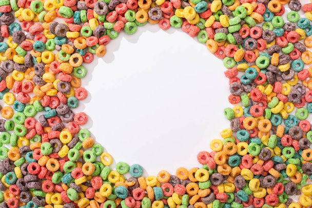 top view of bright multicolored breakfast cereal arranged in round frame on white background - Foto, afbeelding