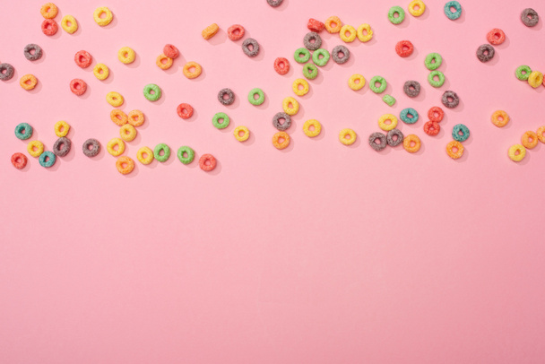 top view of bright multicolored breakfast cereal scattered on pink background - Photo, Image