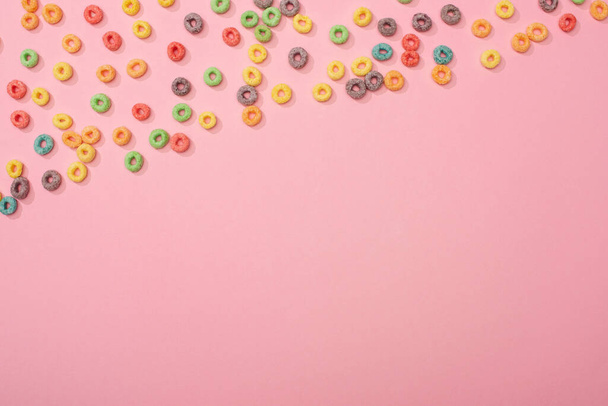 vista superior de los cereales de desayuno de colores brillantes dispersos sobre fondo rosa
 - Foto, imagen