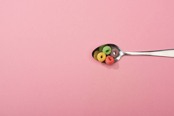 top view of bright colorful breakfast cereal in spoon on pink background - Photo, Image