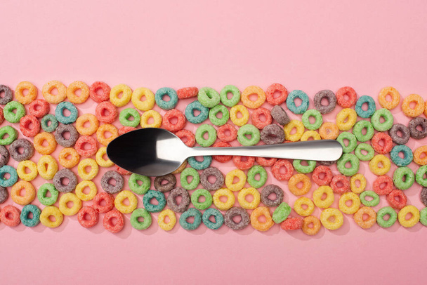top view of bright colorful breakfast cereal and spoon on pink background - Fotografie, Obrázek