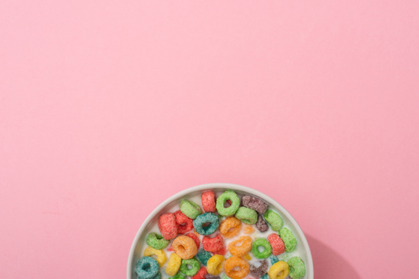 top view of bright colorful breakfast cereal with milk in bowl on pink background - Фото, изображение