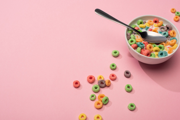 jasné barevné snídaně cereálie s mlékem v misce s lžící na růžovém pozadí - Fotografie, Obrázek
