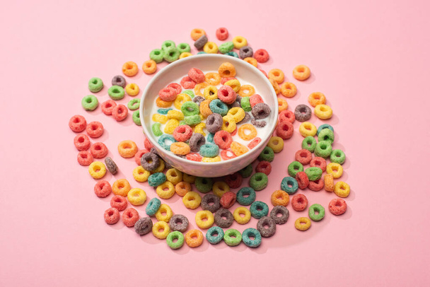 bright colorful breakfast cereal with milk in bowl and around on pink background - Foto, afbeelding