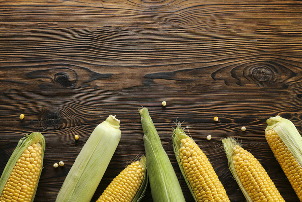 Cobs of ripe raw corn laid on dark wood textured table. Healthy summer food concept. Fresh uncooked corncob. Clean eating habits. Background, top view, close up, flat lay, copy space. - Fotó, kép