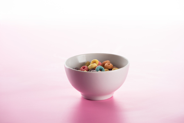 brillante cereal de desayuno multicolor en tazón sobre fondo rosa
 - Foto, Imagen