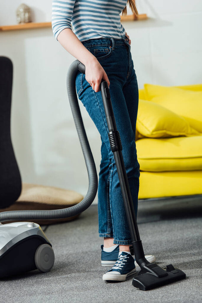Cropped view of woman cleaning carpet with vacuum cleaner in living room - Foto, Bild
