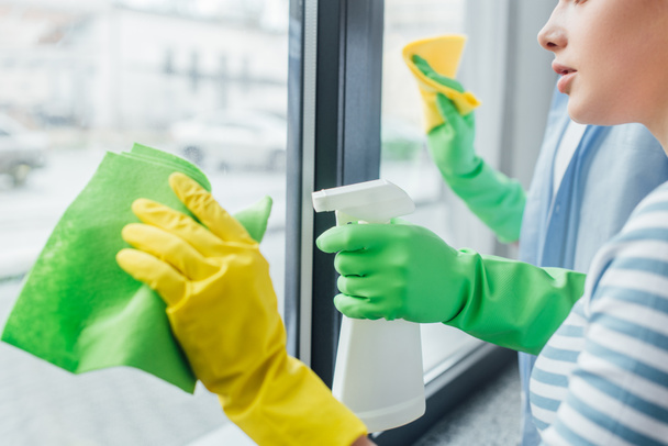 Vista recortada de pareja con trapos y ventana de limpieza de detergente en casa
 - Foto, Imagen