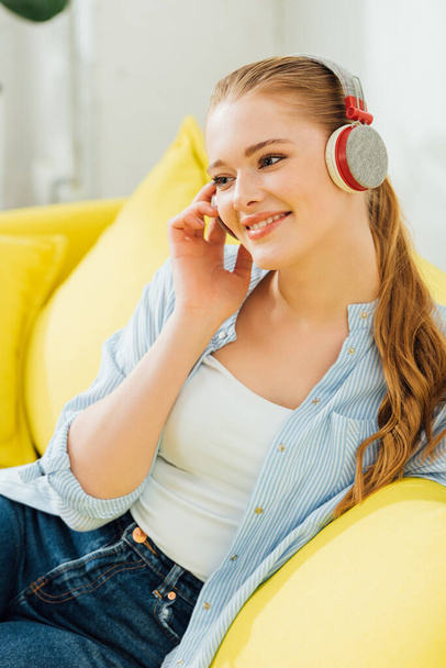 Beautiful smiling woman listening music in headphones at home  - Фото, изображение
