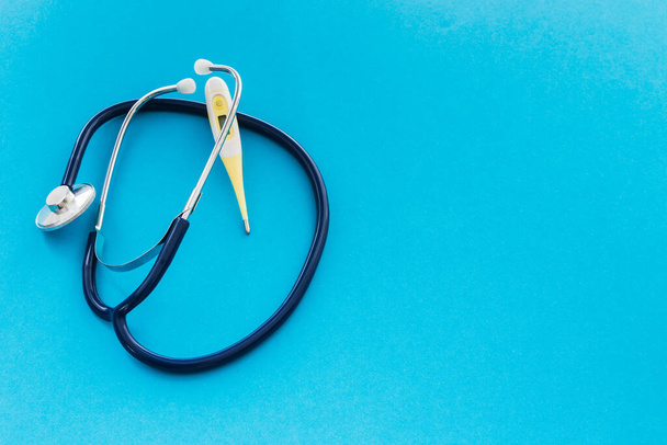 Thermometer und Stethoskop und Maske zum Schutz vor Coronaviren mit Kopierraum auf blauem Hintergrund - Foto, Bild