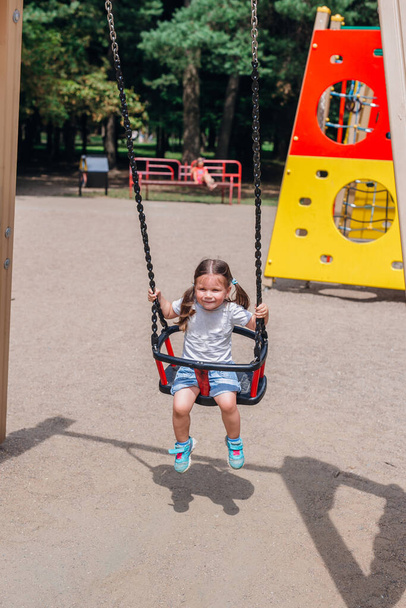 Szczęśliwy wesoły uśmiech słodkie małe dziecko swinging w parku - Zdjęcie, obraz
