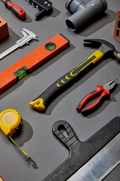 flat lay with measuring tape, calipers, hammer, screwdriver, brush, angle keys, putty knife and spirit levels on grey background - Photo, Image