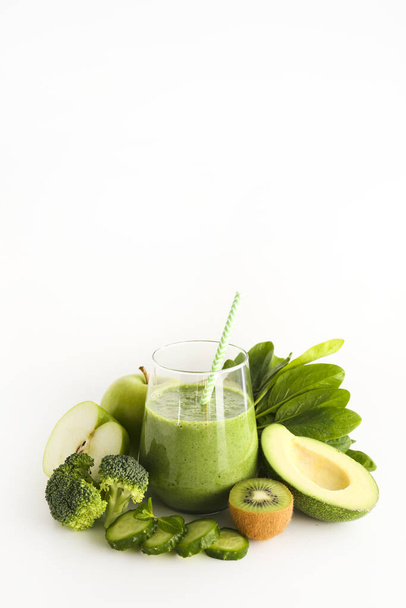 Freshly made green smoothie made of vegetables, fruits, herbs and greens. Glass of blended vegan beverage with ingredients around. Top view, close up, copy space, background. - Photo, Image
