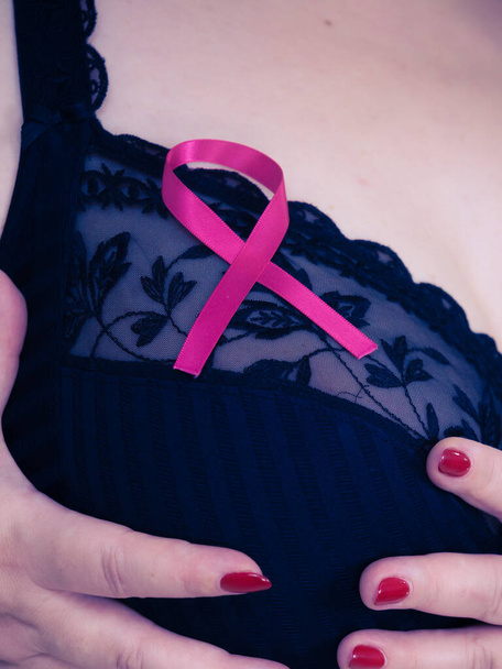 Kobieta z różową wstążką na piersi. Plus rozmiar dojrzałe kobieta noszenie czarny biustonosz bielizna pokazując symbol reprezentujący świadomość, nadzieję i moralne wsparcie dla pacjentów z rakiem piersi. - Zdjęcie, obraz