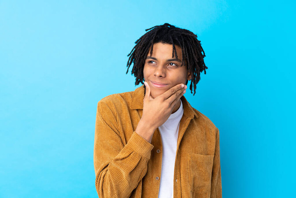 Young African American man with corduroy jacket over isolated blue background thinking an idea - Foto, Bild