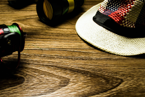  Chapéu, binóculos, carretel de pesca em um fundo de madeira
 - Foto, Imagem