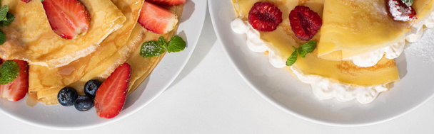top view of tasty crepes with berries on plates on white background, panoramic shot - Photo, Image
