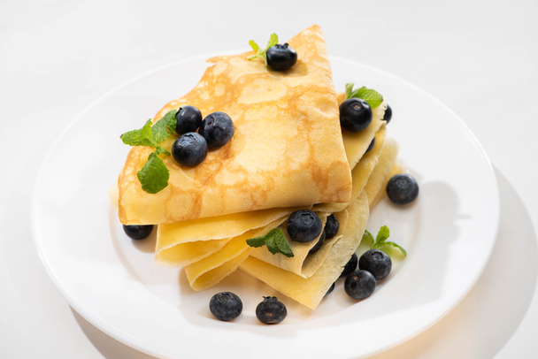 tasty crepes with mint and blueberries on plate on white background - Photo, image