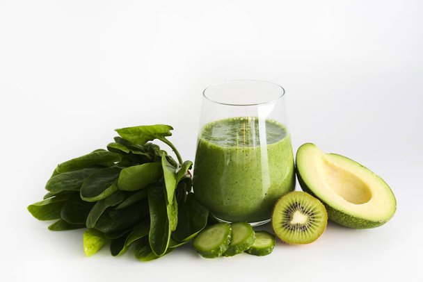 Freshly made green smoothie made of vegetables, fruits, herbs and greens. Glass of blended vegan beverage with ingredients around. Top view, close up, copy space, background. - Fotoğraf, Görsel