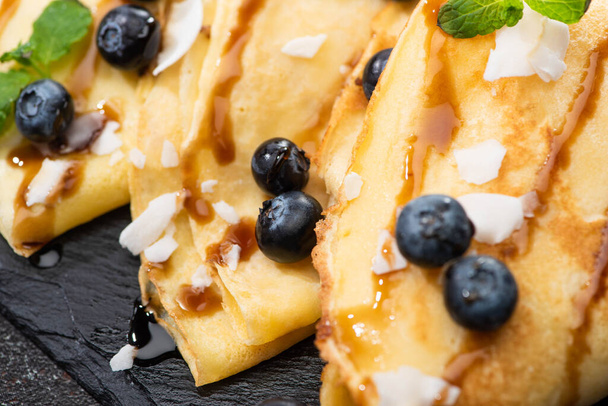 close up view of tasty crepes with blueberries, mint and coconut flakes - Φωτογραφία, εικόνα