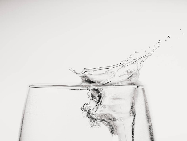 νερό που κινείται σε ένα γεμάτο ποτήρι, απομονωμένο σε λευκό φόντο, έννοια της κίνησης - Φωτογραφία, εικόνα