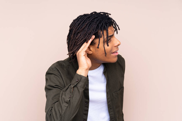 Молодий афроамериканець через відокремлене тло слухає щось, поклавши руку на вухо. - Фото, зображення