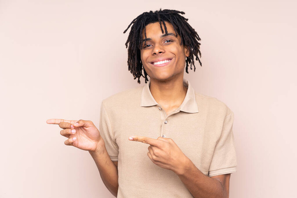 Молодий афроамериканець через ізольоване тло вказує пальцем на бік - Фото, зображення