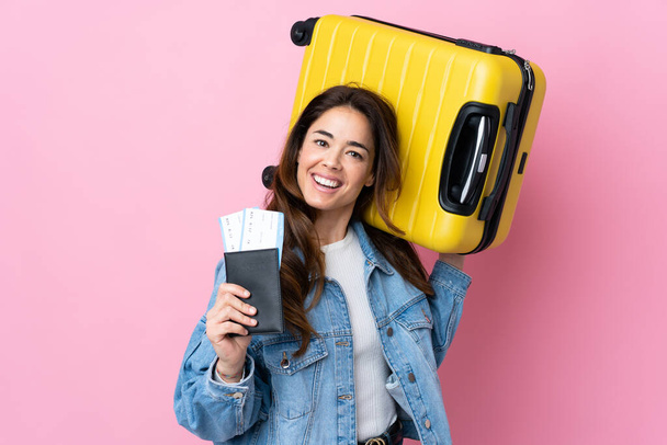 Mujer sobre fondo azul aislado en vacaciones con maleta y pasaporte - Foto, imagen