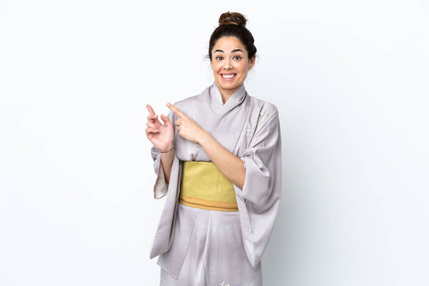 Woman wearing kimono over isolated background frightened and pointing to the side - Photo, Image
