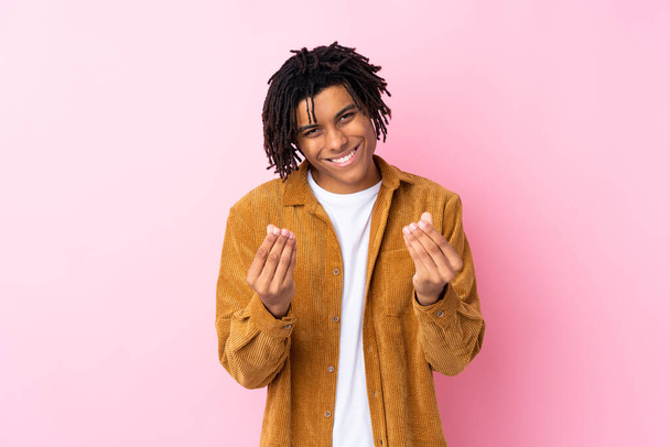 Young African American man with corduroy jacket over isolated pink background making money gesture - Foto, immagini