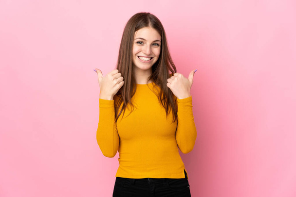 Молода біла жінка ізольована на рожевому тлі з великими пальцями вгору жестом і посмішкою
 - Фото, зображення