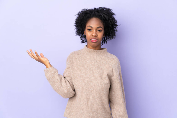 Mladý africký americký žena izolovaný na fialové pozadí dělat pochybnosti gesto - Fotografie, Obrázek