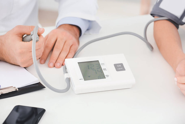 Male doctor measuring blood pressure of female patient in hospital - Fotoğraf, Görsel