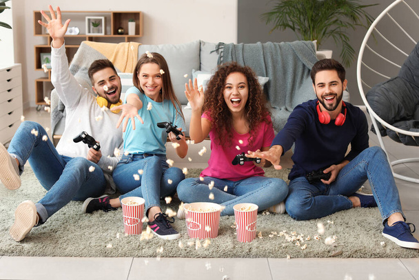 Friends throwing popcorn while playing video game at home - Fotografie, Obrázek