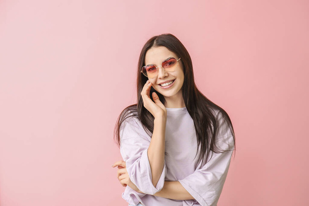 Young woman with stylish sunglasses on color background - Fotó, kép