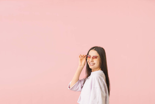 Młoda kobieta w stylowych okularach przeciwsłonecznych na tle koloru - Zdjęcie, obraz