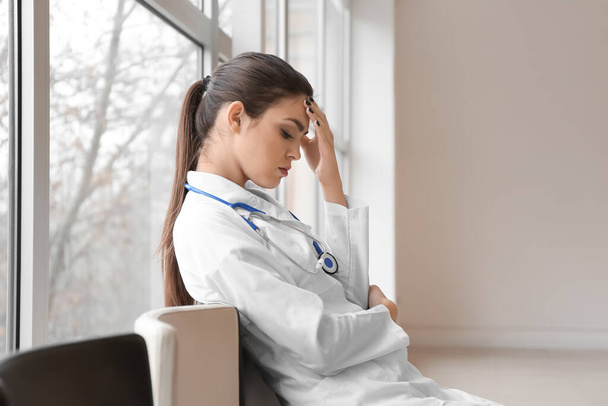 Depressziós női orvos az ablak közelében a klinikán - Fotó, kép
