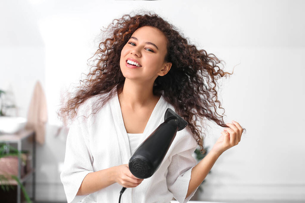 Hermosa joven afroamericana con secador de pelo en casa
 - Foto, Imagen
