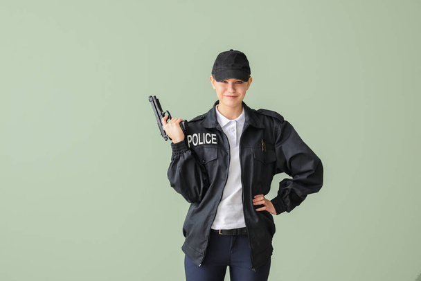 Female police officer with gun on color background - 写真・画像