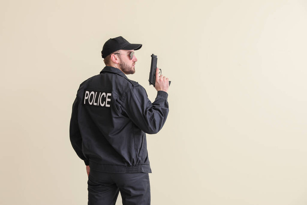 Férfi rendőr pisztollyal a könnyű háttér - Fotó, kép