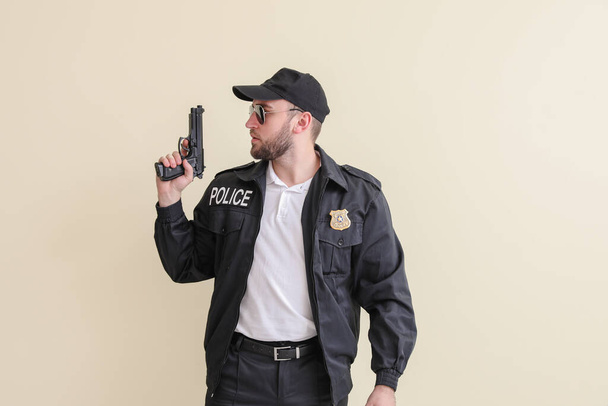Male police officer with gun on light background - Foto, afbeelding