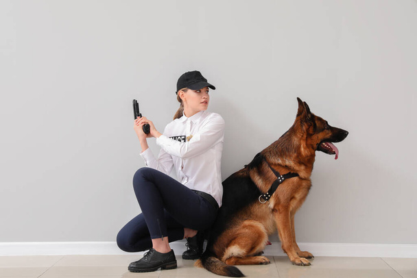 軽壁の近くに犬を持つ女性警察官 - 写真・画像