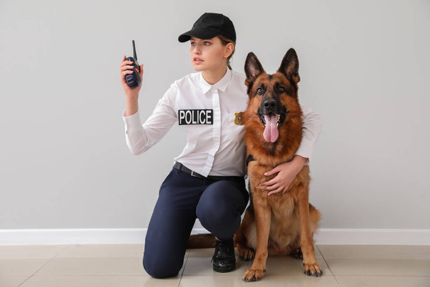 Naispoliisi koiran kanssa lähellä valoseinää
 - Valokuva, kuva