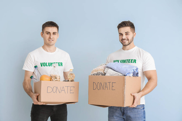 Volunteers with donations for poor people on color background - Photo, Image
